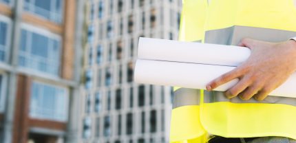 close-up-man-safety-vest-with-building-plans