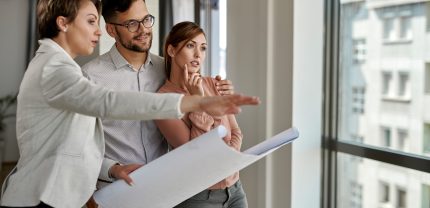 Young couple analyzing housing project while buying a new apartment.